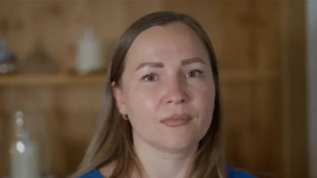 Marina Perederii, cabelos castanhos longos e lisos e vestindo uma blusa azul