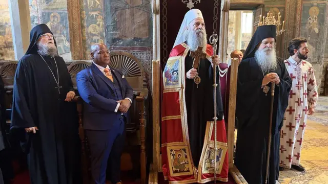 Pravoslavni sveštenici stoje u odorama, drugi među njima pastor u plavom odelu