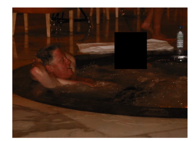 Ông Bill Clinton đang nằm ngửa trong một bồn tắm nước nóng, người bên cạnh đã được che mặt 