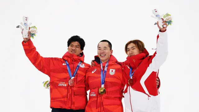 Золотой медалист Кира Кимура из сборной Японии, серебряный медалист Рёма Кимата из сборной Японии и бронзовый медалист Йимин Су из сборной Китайской Народной Республики празднуют победу после финала мужского сноуборда в дисциплине «Биг-эйр» в первый день зимних Олимпийских игр Milano Cortina 2026 в сноу-парке Ливиньо 7 февраля 2026 года в Ливиньо, Италия.