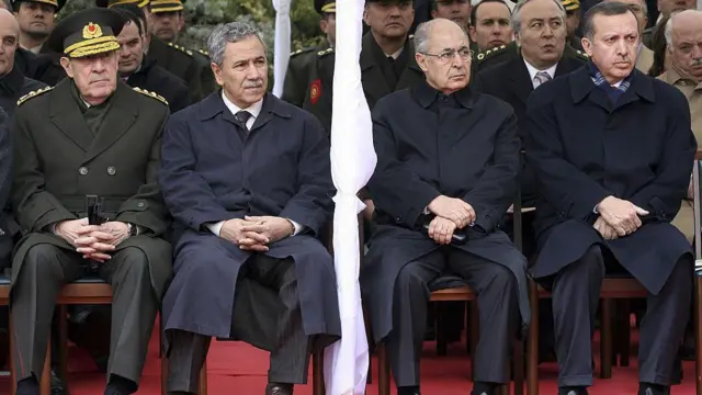 Dönemin Genelkurmay Başkanı Yaşar Büyükanıt, TBMM Başkanı Bülent Arınç, Cumhurbaşkanı Ahmet Necdet Sezer ve Başbakanı Recep Tayyip Erdoğan (Soldan sağa), 19 Nisan 2007'de, Ankara'daki bir törende yan yana oturuyor. Herkes palto giymiş durumda. Hepsi de aynı noktaya bakıyor.