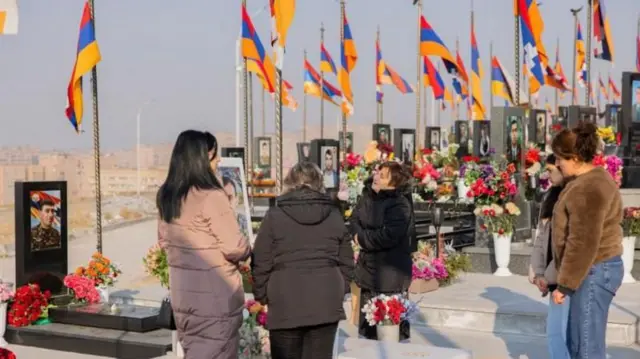 Ermenistan'da bir asker mezarlığını ziyaret eden kişiler