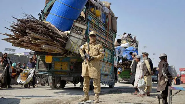 تصویری از نقطعه مرزی افغانستان با پاکستان. در این تصویر یک سرباز مرزی طالبان دیده میشود. در عقب او یک لاری حامل وسایل مهاجران قرار دارد. در تصویر شماری مهاجران نیز دیده میشوند.