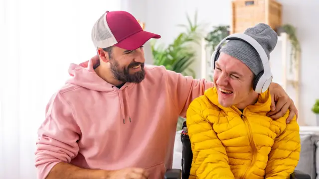 رجل من ذوي الإعاقة يستمتع بلحظة تواصل هادئة مع مقدم الرعاية خلال جلسة علاج بالفن والموسيقى