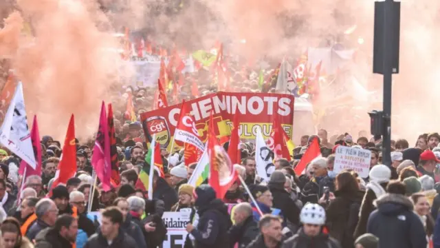 Protesters wave flags and banners during a rally called by French trade unions in Toulouse, southwestern France, on January 19, 2023. - A day of strikes and protests kicked off in France on January 19, 2023 
