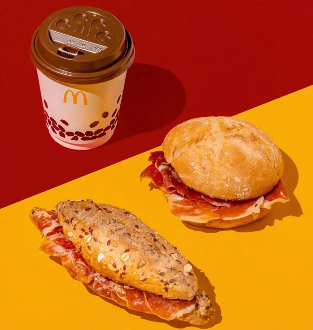 Сендвічі з хамоном та паперовий стаканчик кави з логотипом Макдональдс на жовтому та червоному тлі