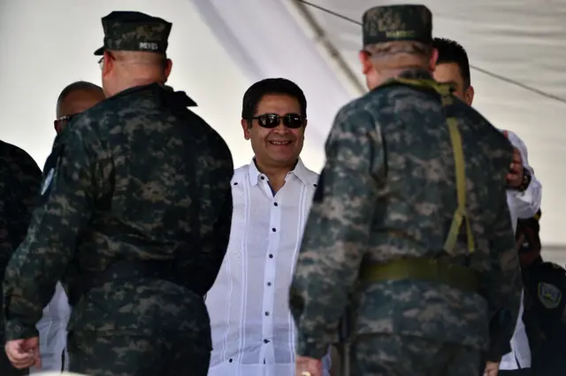 Juan Orlando Hernández sonríe frente a militares siendo presidente de Honduras en 2019.