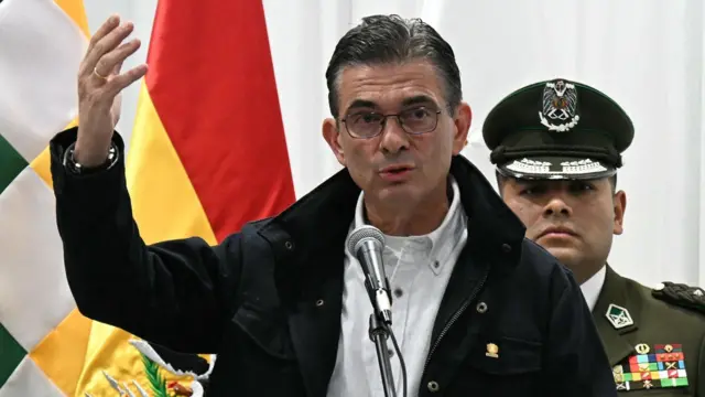 El presidente Rodrigo Paz, que lleva lentes, una camisa blanca y una chaqueta negra, habla frente a un micrófono.