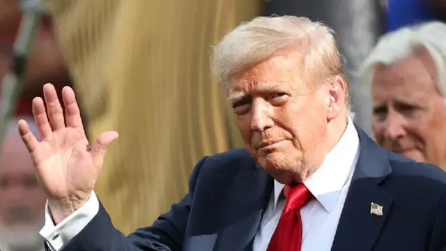 カメラに向かって右手を挙げてあいさつするドナルド・トランプ大統領(資料写真)