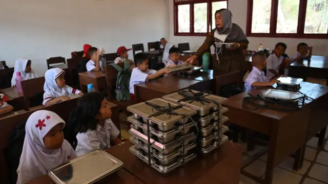 Seorang guru membagikan ompreng berisi menu Makan Bergizi Gratis (MBG) yang akan dibagikan kepada para murid di SD Negeri 1B 152982 di Kelurahan Tukka, Kecamatan Tukka, Tapanuli Tengah, Sumatera Utara, Selasa (27/1/2026).