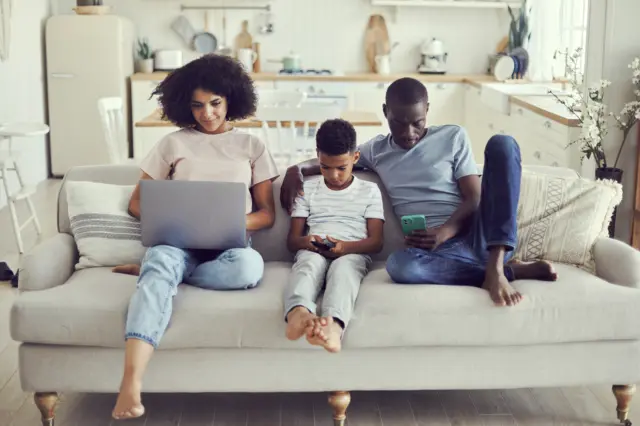 Une famille de trois les yeux rivés sur leurs écrans