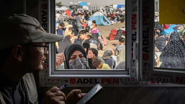  کارمند مرد با تلفن همراه در دست و زن پشت باجه