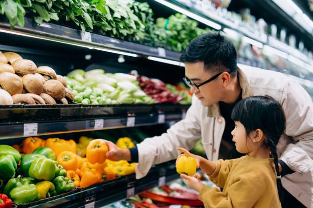 adulto e criança escolhem verduras no mercado
