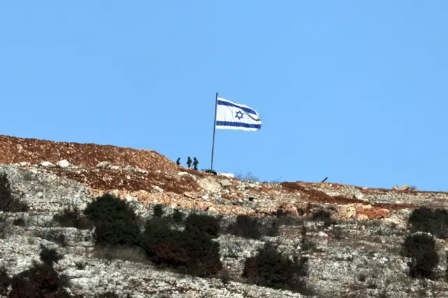 Soldados israelenses ao ladoo jogo do foguetinho que da dinheirosua bandeira na fronteira com o sul do Líbano