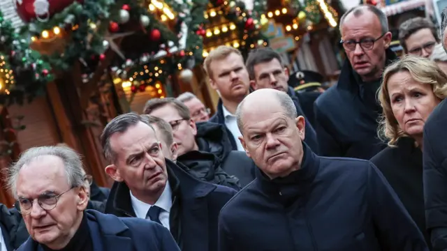 German Chancellor Olaf Scholz, accompanied by other officials, visits the site of a car ramming attack at the Christmas market in Magdeburg, Germany.