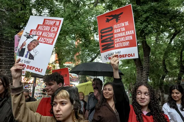 Акция протеста против саммита НАТО в Анкаре — протестующая держит плакат с надписью «Не нарушайте общественный порядок ради Трампа»