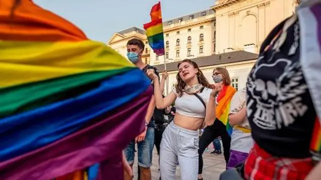 Ludzie – niektórzy owinięci w tęczowe flagi – tańczą, biorąc udział w tęczowym flashmobie dyskotekowym przed Pałacem Prezydenckim w Warszawie, 11 czerwca 2020 roku.