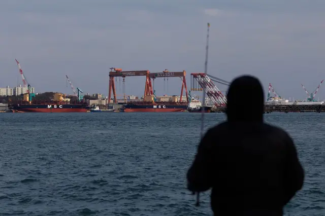 멀리서 조선소를 바라보는 한 사람의 뒷모습