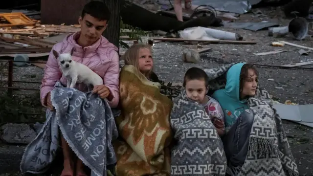 Діти, загорнуті в ковдри, біля будинку, що постраждав від обстрілу 