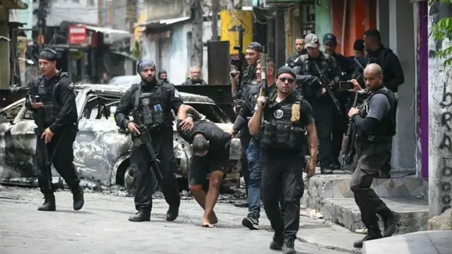 Policiais escoltam um suspeito preso durante a Operação Contenção na favela da Vila Cruzeiro, no complexo da Penha, no Rio de Janeiro, Brasil, em 28 de outubro de 2025
