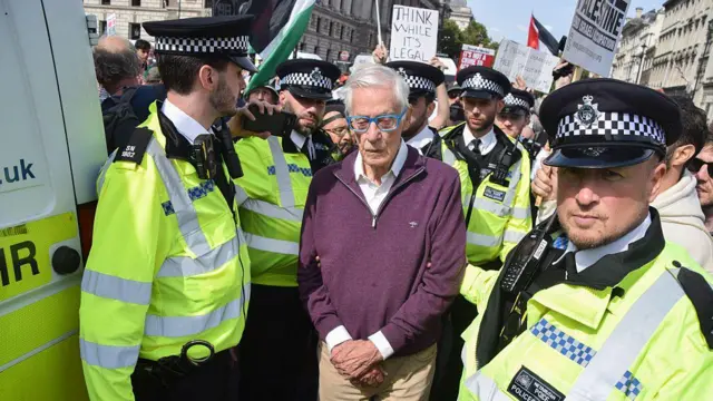 Полицейские конвоируют к фургону пожилого человека