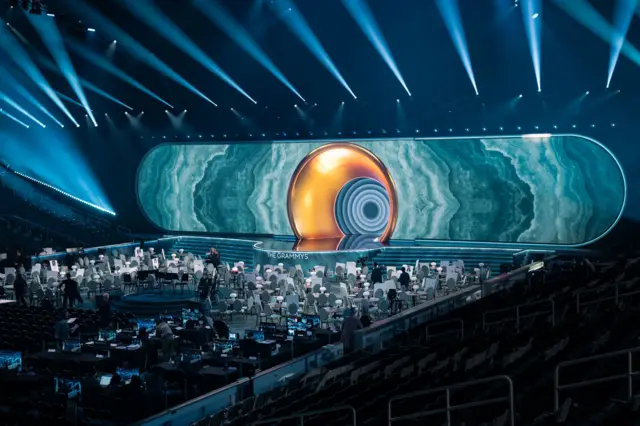 Wide shot of di 2025 Grammy stage, e show di giant LED screens and 20-foot golden sculpture wey dey inspired by a Gramophone machine.
