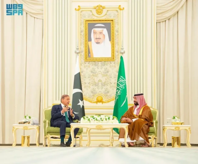 نخست‌وزیر پاکستان محمد شهباز شریف و ولیعهد عربستان محمد بن سلمان در ریاض، در کنار هم نشسته و در حال گفت‌وگو هستند، پرچم‌های دو کشور در پشت سر آنهاست