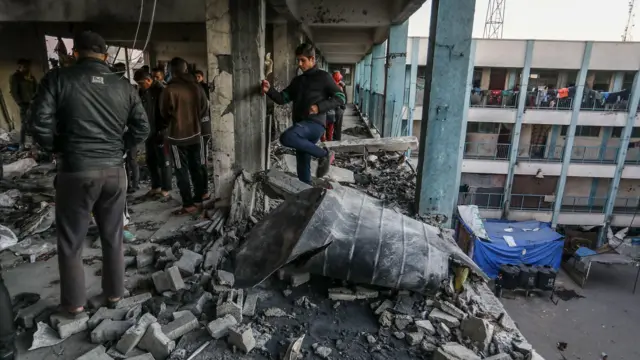 Palestinians inspect damage afta one Israeli air strike on one school housing displaced families for Khan Younis, southern Gaza (16 December 2024)