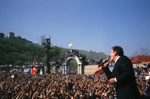 Ferdi Tayfur sahnede şarkı söylüyor, kalabalıklar eşlik ediyor