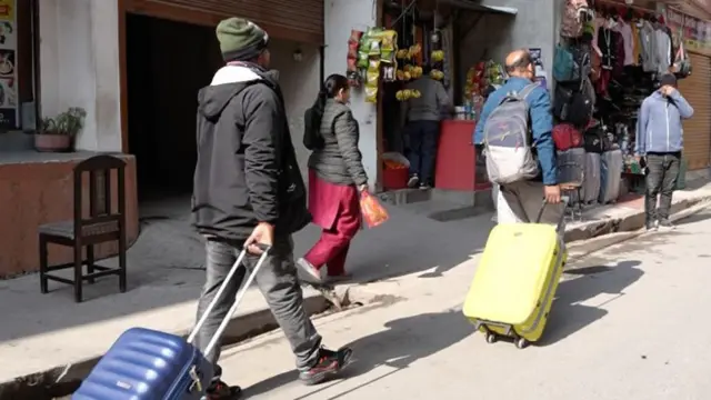 सुटकेश डोर्‍याएर तानीरहेका दुई जना श्रमिकहरूको तस्बीर