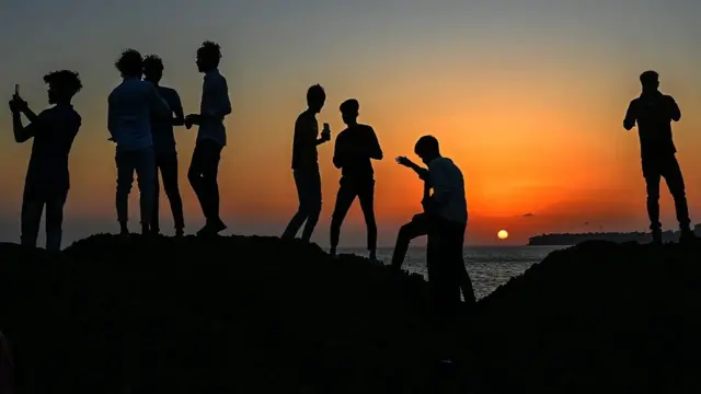 Молодь біля моря, на тлі заходу сонця