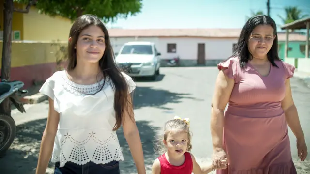 Família com duas meninas e mae andando na rua