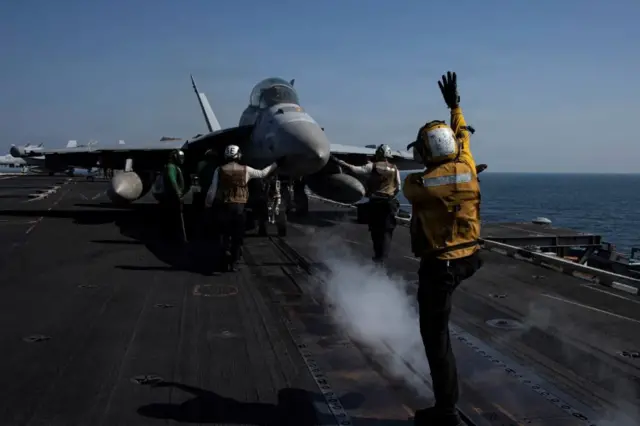 Personal del USS Abraham Lincoln frente a un jet militar