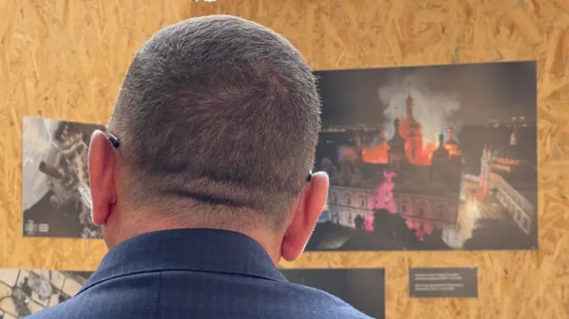 Валерій Залужний дивиться на виставку, присвячену наслідкам російського обстрілу Києво-Печерської лаври
