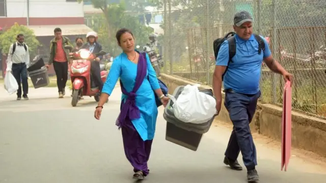 मतदान भइसकेपछि गणनाका लागि मतपेटिका ओसार्दै एक महिला तथा एक पुरुष कर्मचारी