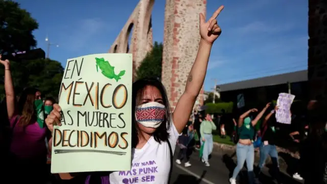 Manifestante erguendo o braçojogar double blazeprotesto na rua, com cartaz dizendo: 'En México las mujeres decidimos'