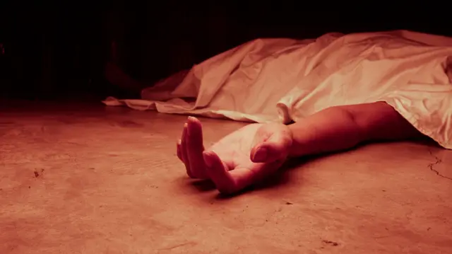 The dead woman's body. Focus on hand, red tone color processed