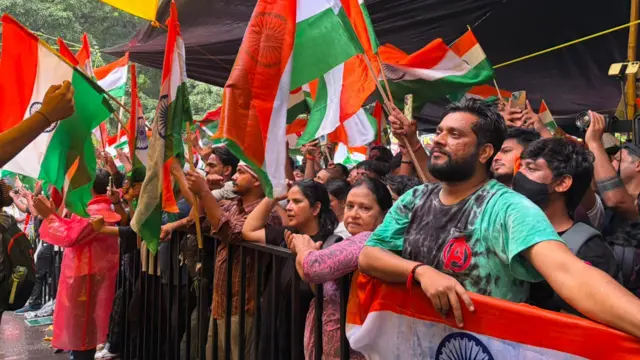 Protesters can be seen waving the Indian flag