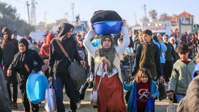 Gazze'nin kuzeyindeki evlerine yürüyerek dönmeye çalışan kalabalık bir kitle, kadınlar çocukları ve taşıdıkları eşyalarla
