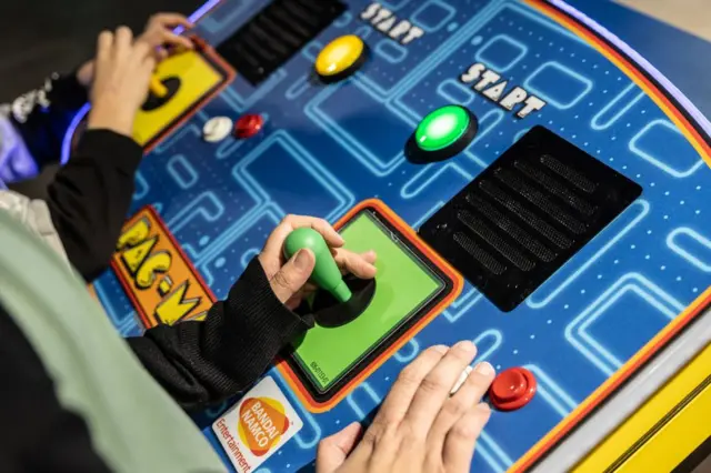 Mãos de crianças em um fliperama