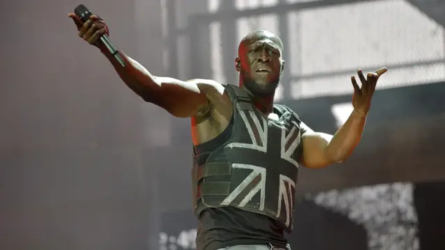 Репер Stormzy на головній сцені Гластонбері у 2019 році в жилеті з британським прапором, розробленим Бенксі