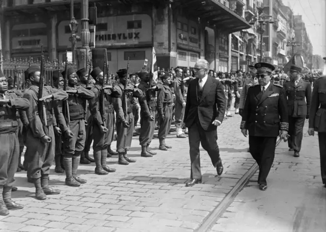 Le ministre français de l'Outre-mer Marius Moutet (2e à gauche) inspecte les Tirailleurs sénégalais avant leur retour à Dakar à bord du SS Pasteur, un navire à vapeur à turbine pour le transport de troupes, en avril 1946 dans le port de Marseille.