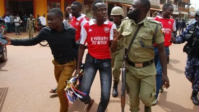Arsenal fans wearing the red and white shirts being arrested by police in 2023