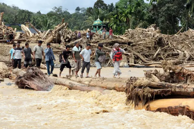 Warga berjalan melintasi sungai dengan jembatan darurat di Desa Aek Garoga, Kecamatan Batang Toru, Kabupaten Tapanuli Selatan, Sumatera Utara, Sabtu (29/11/2025). 