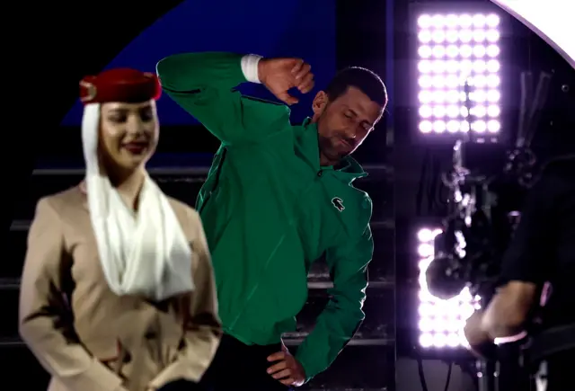 novak đoković se zagreva pred meč na australijan openu, ispred njega je devojka obučena kao stjuardesa neke arapske avio-kompanije