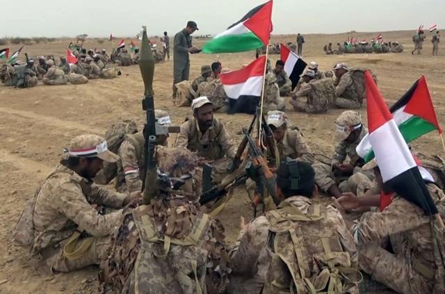 Combatentes Houthi sentados ao redor de uma bandeira