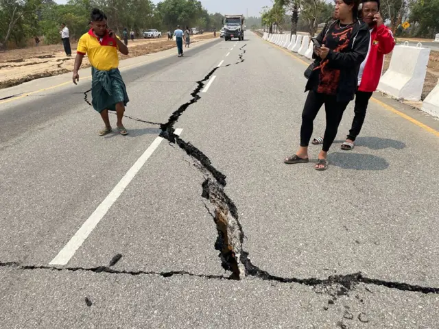 People look at a damaged road on the Naypyidaw-Yangon highway after an earthquake, in Nay Pyi Taw, Myanmar, 28 March 2025.