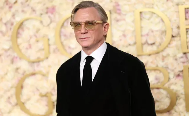 Daniel Craig usa óculos e terno