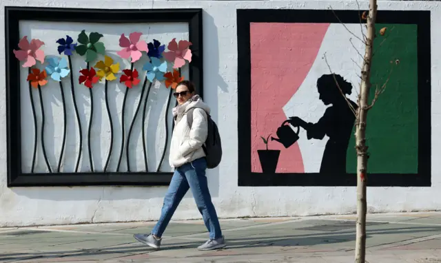 زنی در حال عبور در خیابانی در تهران