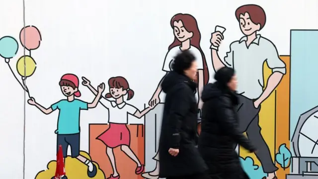 가족이 그려진 벽화 앞을 지나가는 사람들